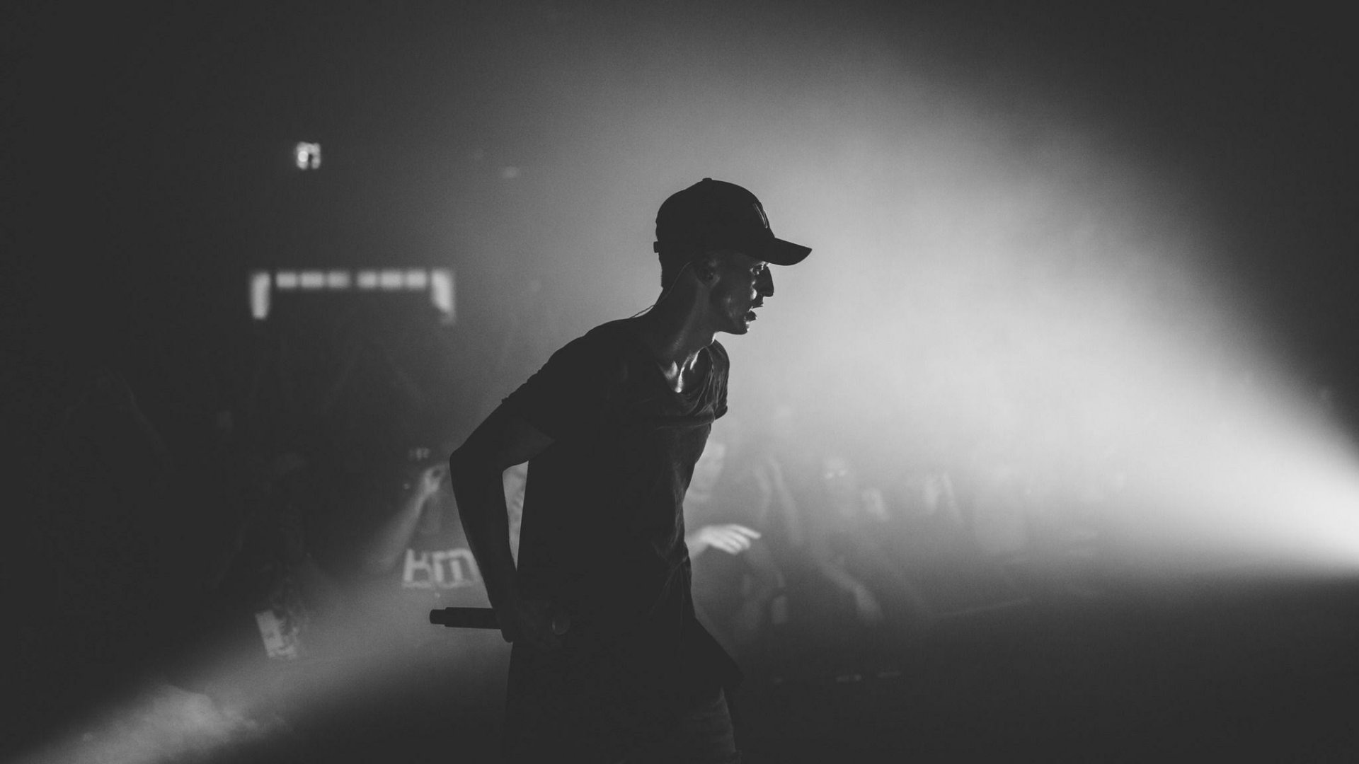 A dynamic black and white image of a musical performer on stage, captured mid-performance with dramatic lighting. This HD wallpaper embodies the energy of live music.