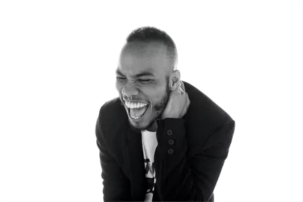 HD desktop wallpaper featuring Anderson .Paak in a black and white photo, laughing and touching his ear.