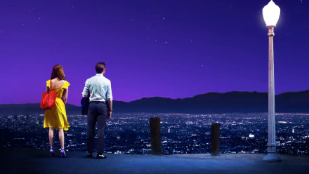 HD desktop wallpaper featuring Mia and Sebastian Wilder characters from the movie La La Land, portrayed by Ryan Gosling and Emma Stone, standing under a streetlamp overlooking a starry cityscape.