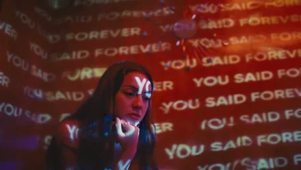 HD desktop wallpaper featuring brunette American singer and actress Olivia Rodrigo with the phrase YOU SAID FOREVER projected repeatedly in the background.