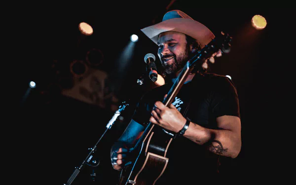 HD wallpaper featuring a performer with a guitar onstage, evoking the musical essence of Shakey Graves.