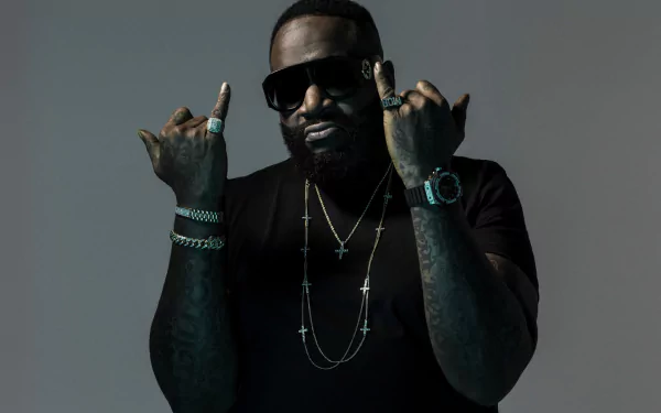 HD desktop wallpaper featuring a man with sunglasses, making hand gestures, adorned with jewelry, set against a gray background.