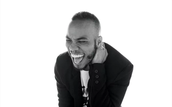 HD desktop wallpaper featuring Anderson .Paak in a black and white photo, laughing and touching his ear.