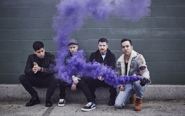 HD desktop wallpaper featuring a group of four musicians sitting against a wall with purple smoke for a creative and edgy background look.