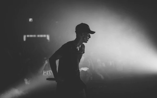 A dynamic black and white image of a musical performer on stage, captured mid-performance with dramatic lighting. This HD wallpaper embodies the energy of live music.
