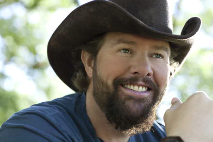 Smiling man with beard wearing cowboy hat in nature setting as HD desktop wallpaper background.