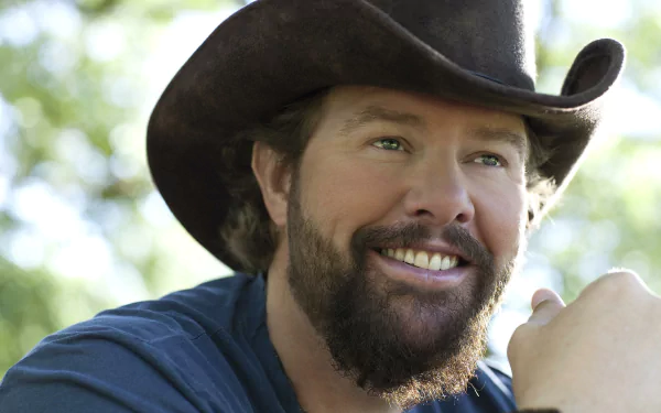 Smiling man with beard wearing cowboy hat in nature setting as HD desktop wallpaper background.