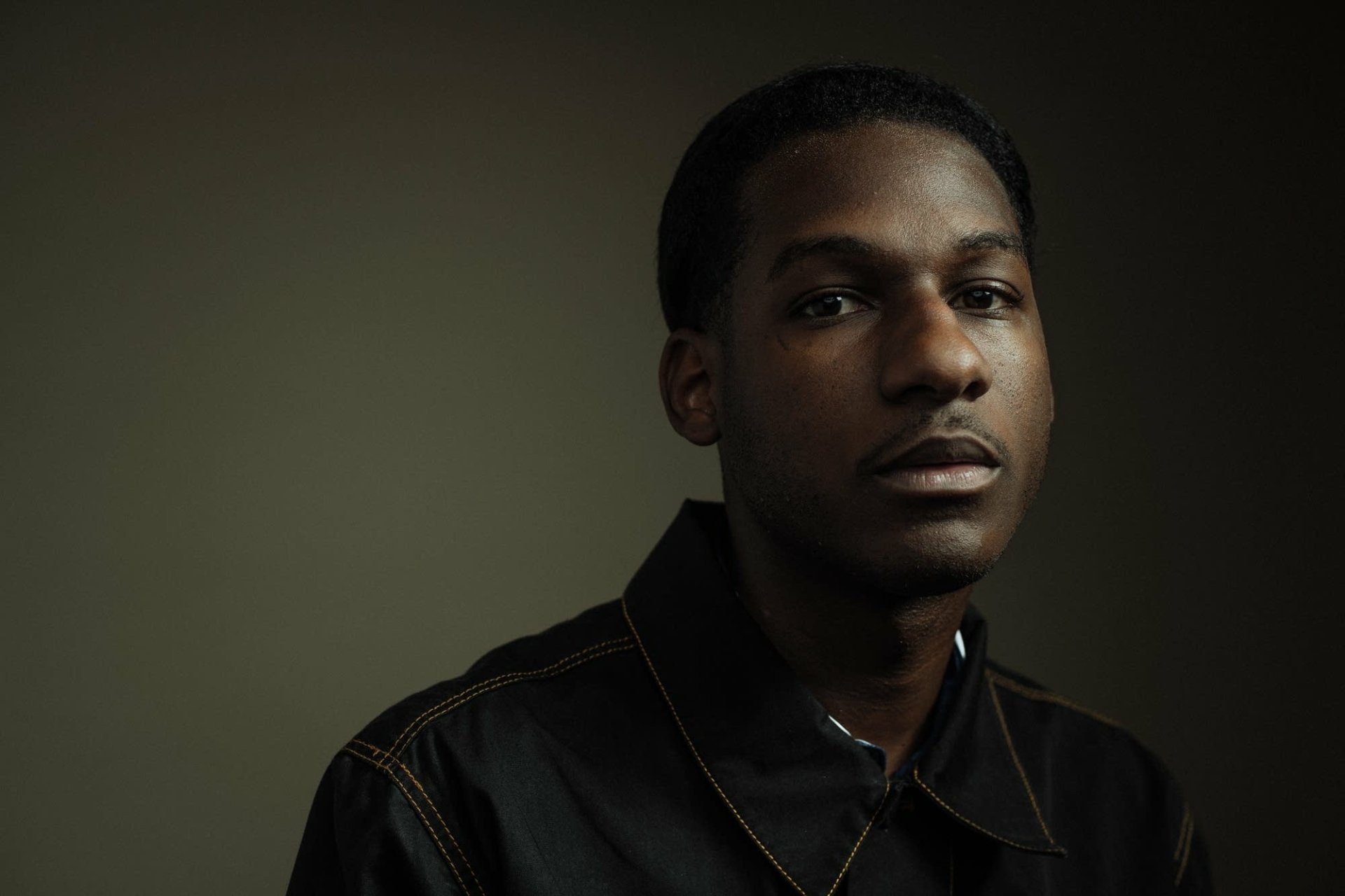 A striking HD desktop wallpaper featuring Leon Bridges, capturing the essence of music with his focused expression against a muted background.
