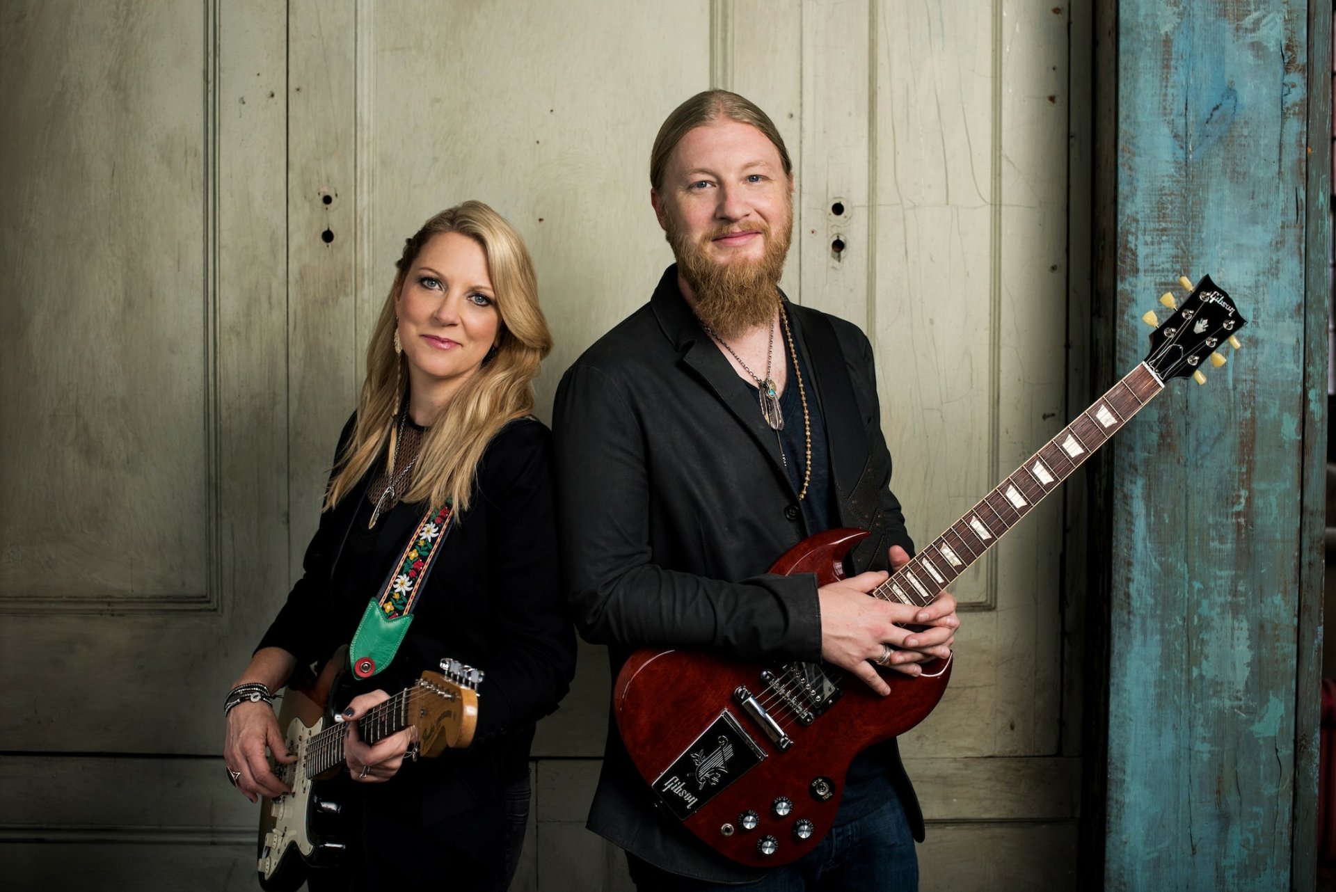 A striking HD wallpaper featuring the Tedeschi Trucks Band, showcasing a guitarist and vocalist in a stylish pose against a textured backdrop, embodying the spirit of music.