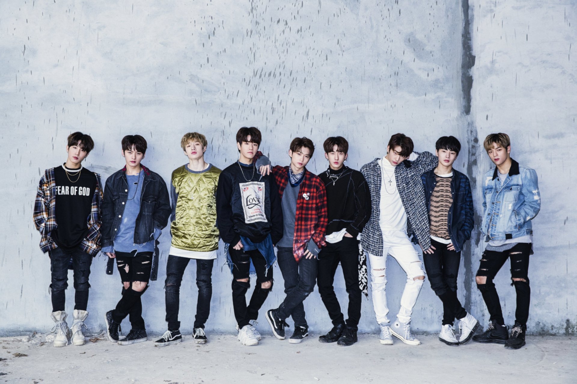 HD desktop wallpaper featuring Stray Kids, a popular K-pop boy band, posing against a textured gray wall with casual streetwear styles.