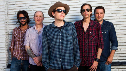 HD desktop wallpaper featuring the band The Wallflowers posing in front of a white brick wall background.