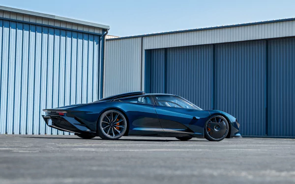 4K Ultra HD PC desktop wallpaper of a blue McLaren Speedtail supercar vehicle parked by hangar doors, sleek aerodynamic profile against a clear sky.