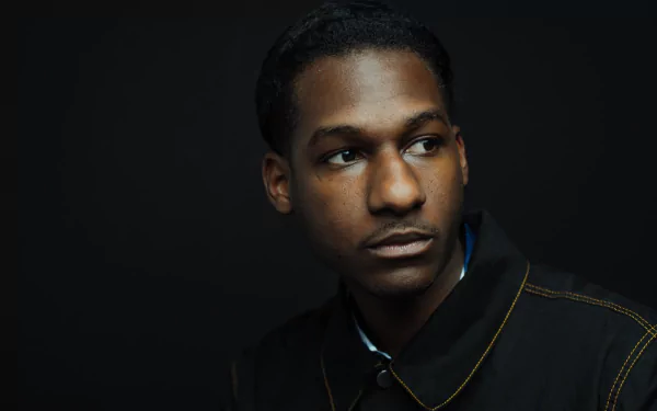 HD desktop wallpaper featuring a portrait of a man against a dark background, giving a contemplative look, tagged with Leon Bridges.