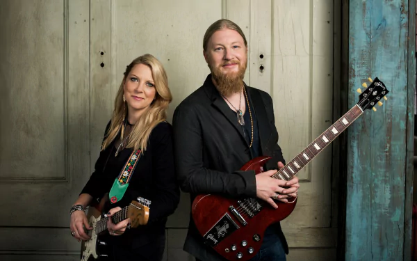 A striking HD wallpaper featuring the Tedeschi Trucks Band, showcasing a guitarist and vocalist in a stylish pose against a textured backdrop, embodying the spirit of music.