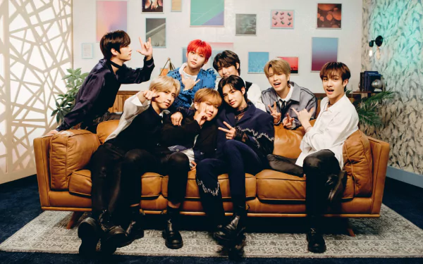 HD PC wallpaper featuring the K-pop boy band Stray Kids posing together on a brown couch in a stylish indoor setting.