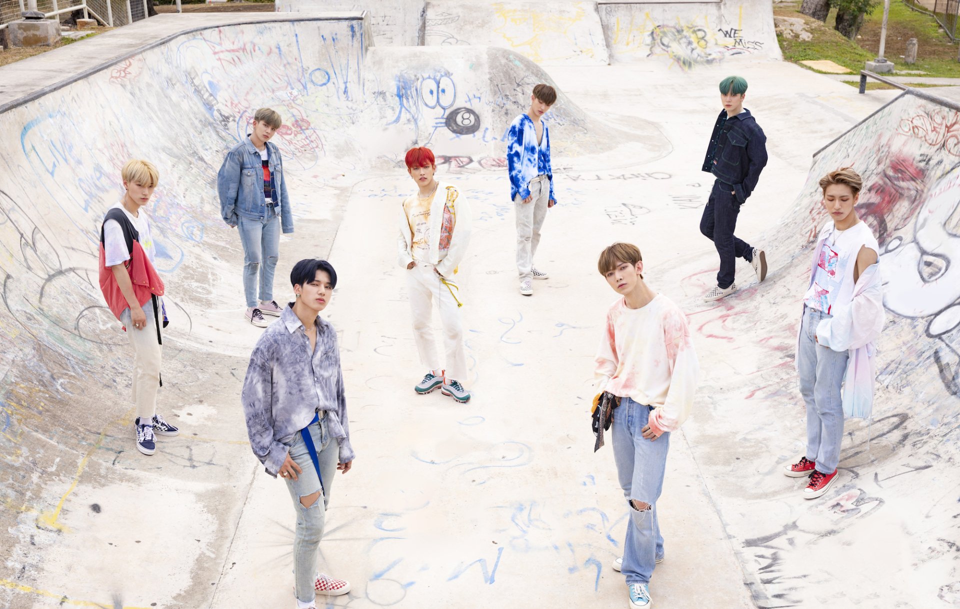 ATEEZ band members posing casually in a graffiti-covered skate park, offering a stylish and youthful vibe for HD desktop wallpaper and background.