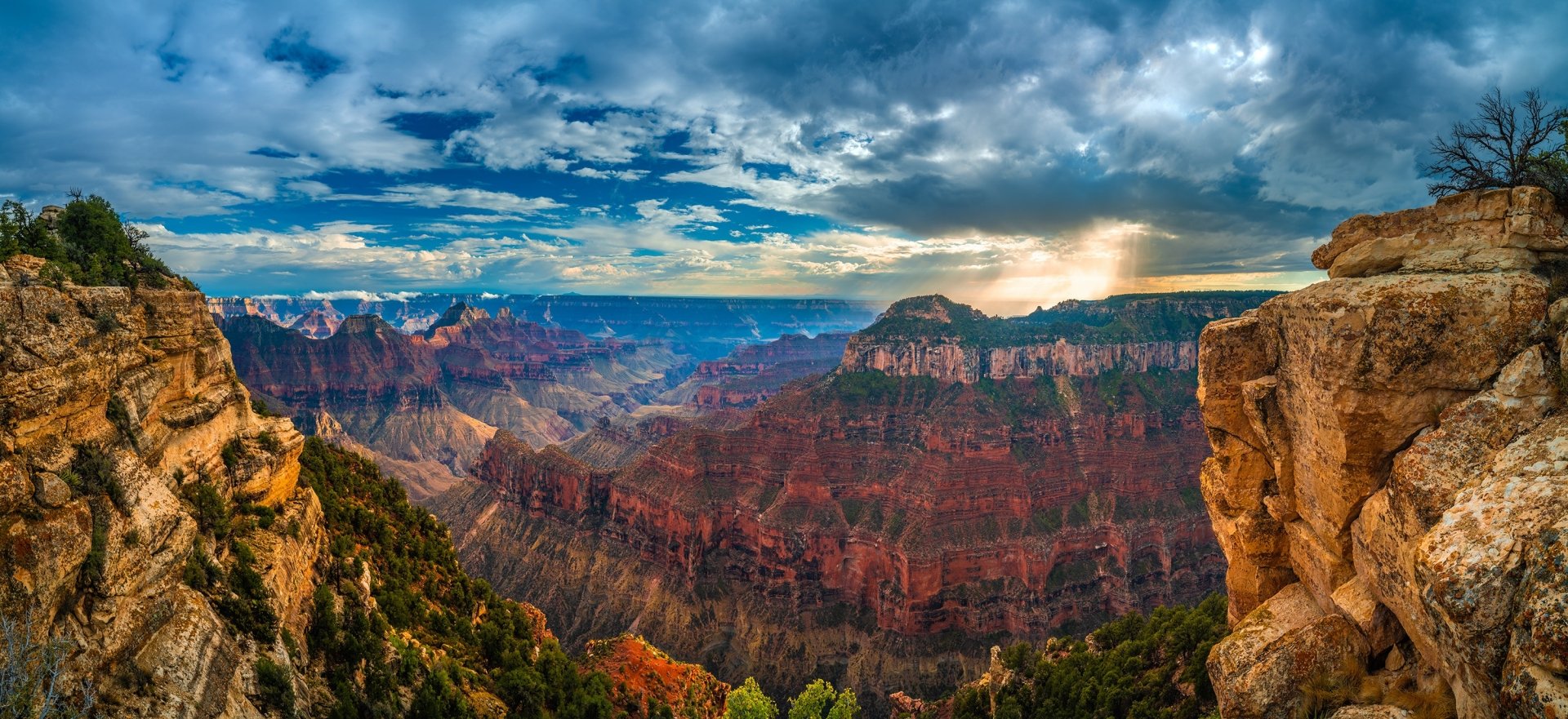HD PC desktop wallpaper: panoramic Arizona Grand Canyon nature scene — layered red rock cliffs, deep canyon valleys and dramatic cloudy sky.