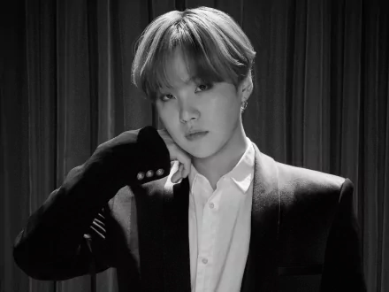 Black and white HD wallpaper of Suga (Min Yoongi) from BTS, dressed in a suit, with a contemplative expression, representing K-pop and music artistry.