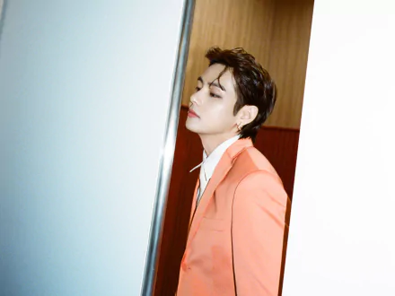 HD PC wallpaper of V (Kim Taehyung) from BTS, dressed in a coral suit, showcasing his signature K-pop style and music star presence.