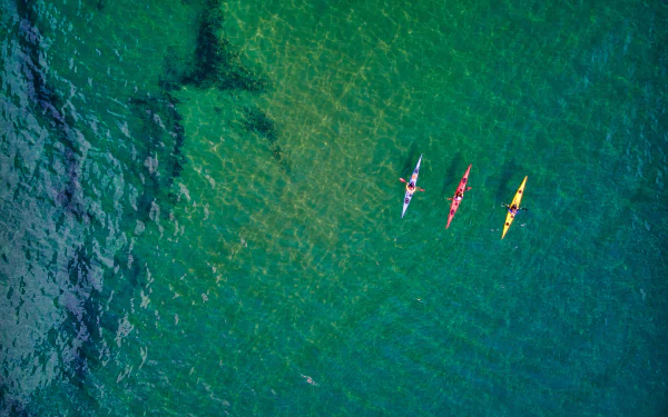  A trio of colourful kayaks navigate the crystal clear shallows along the Jurassic Coast, Devon, UK by Red Zeppelin