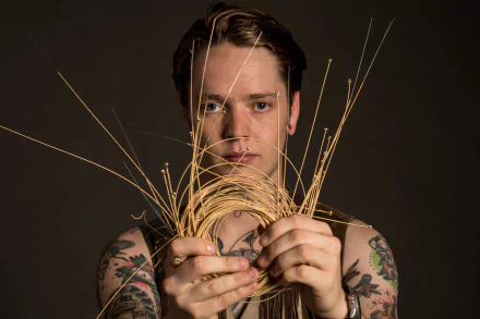 HD desktop wallpaper featuring a person holding strings with tattoos on arms against a dark background.