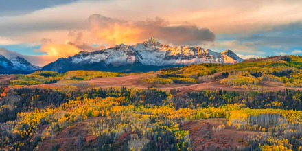 4K Ultra HD desktop wallpaper showcasing a vibrant fall landscape with colorful foliage and a majestic mountain range under a glowing sky.