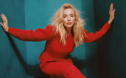 HD desktop wallpaper of blonde celebrity Jodie Comer posing against a teal background, wearing a vibrant red outfit.
