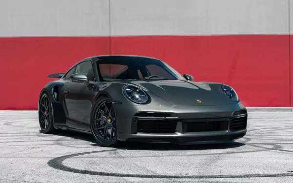 Sleek Porsche 911 Turbo S in metallic gray showcased against a red and white wall, captured in stunning 8K Ultra HD for a high-quality PC desktop wallpaper.