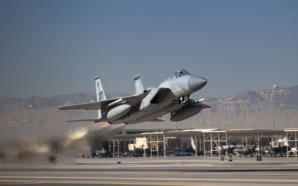 A McDonnell Douglas F-15 Eagle jet fighter warplane accelerating on a runway with mountains and hangars in the background, captured in 4K Ultra HD resolution.