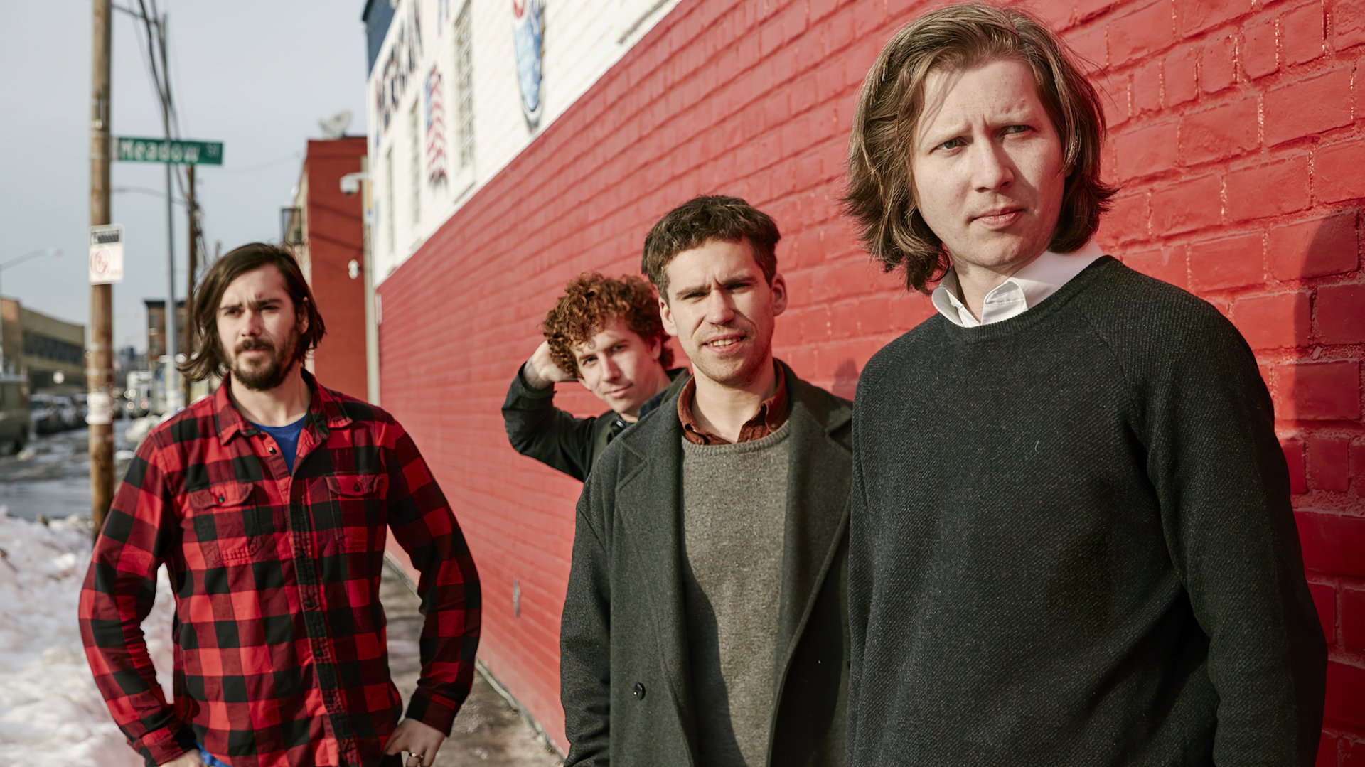 HD desktop wallpaper featuring the band Parquet Courts standing against a red brick wall.