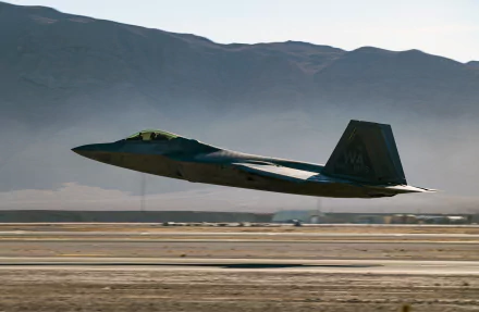 Lockheed Martin F-22 Raptor jet fighter flies low over a runway with mountains in the background, captured in 4K Ultra HD for a military-themed desktop wallpaper.