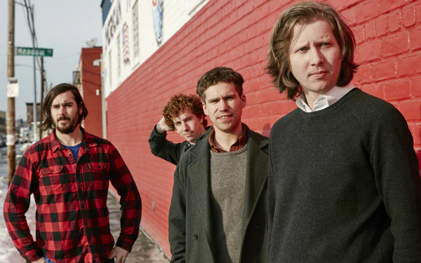 HD desktop wallpaper featuring the band Parquet Courts standing against a red brick wall.