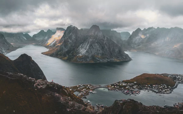 4K Ultra HD photography of Lofoten: dramatic fjords and jagged peaks above a coastal village, moody clouds — PC desktop wallpaper and background.