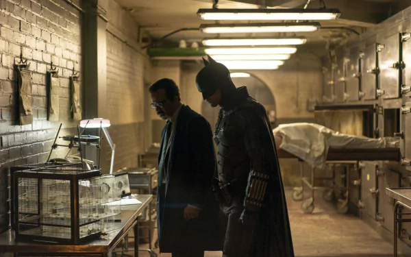 HD movie wallpaper featuring Robert Pattinson as Batman in his Batsuit alongside Jeffrey Wright as Commissioner Gordon in a dimly lit, industrial setting from The Batman.