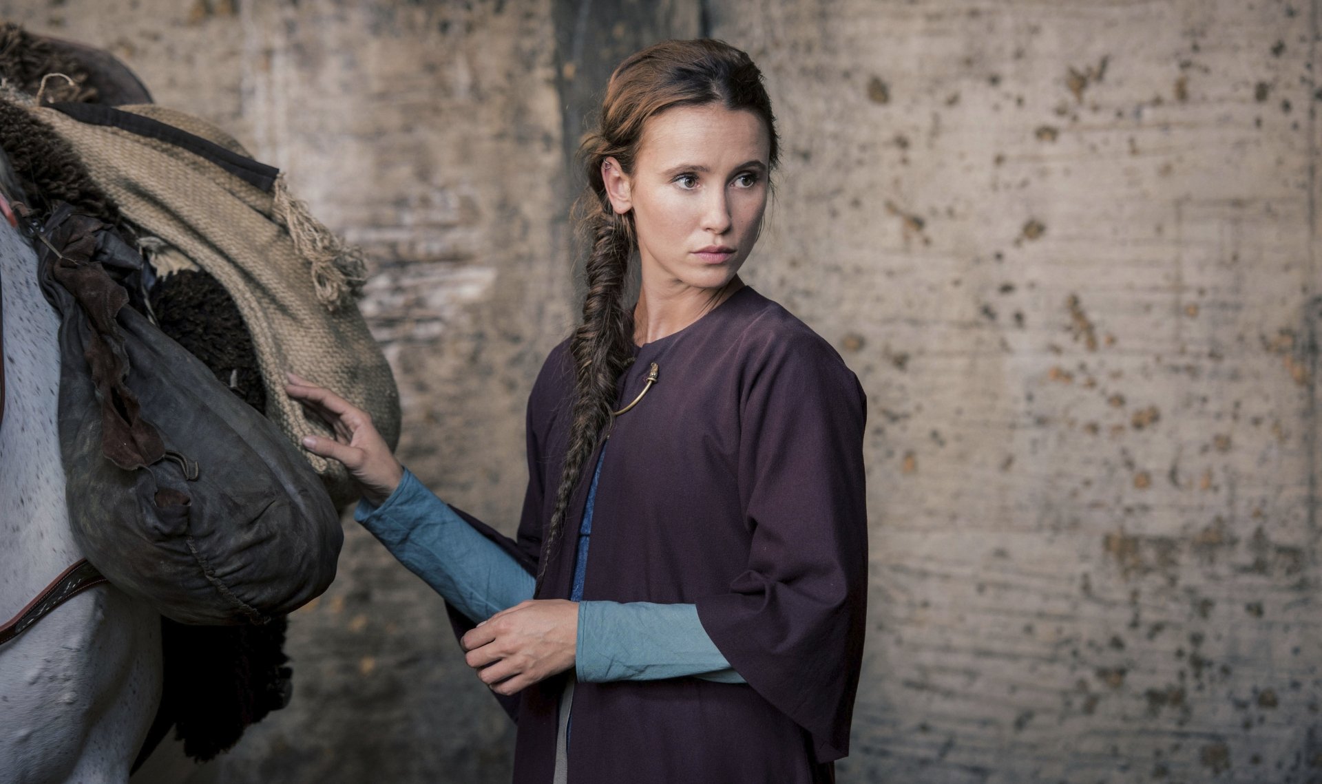 A 4K Ultra HD desktop wallpaper featuring a scene from the TV show The Last Kingdom, showing a woman in period attire adjusting a saddle against a rustic backdrop.