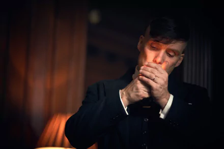 4K desktop wallpaper: moody close-up of a period TV drama character in a tailored suit lighting a cigarette in a dim, wood-paneled interior.
