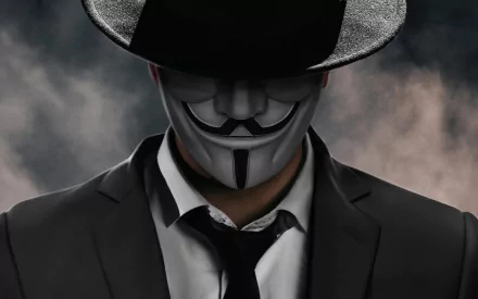 HD PC desktop wallpaper: anonymous figure in suit and hat wearing a Guy Fawkes mask, framed by smoky background — technology and anonymity theme.