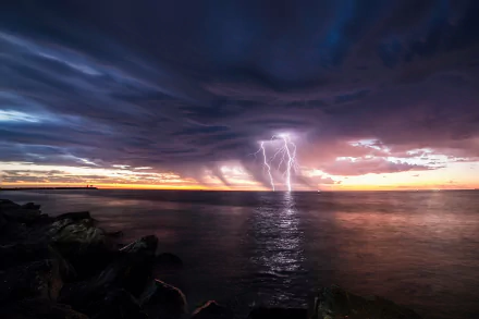 HD PC desktop wallpaper: horizon photography of a stormy sunset over the ocean with dramatic clouds and multiple lightning strikes reflecting on calm water.