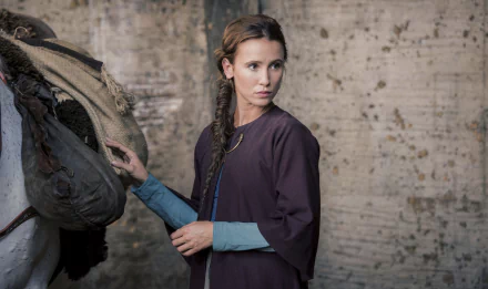 A 4K Ultra HD desktop wallpaper featuring a scene from the TV show The Last Kingdom, showing a woman in period attire adjusting a saddle against a rustic backdrop.