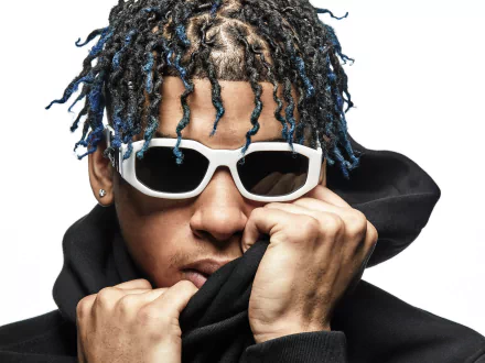 Close-up portrait of a hip-hop artist with blue-tipped braids and white sunglasses, pulling up a black hoodie — music-themed 4K Ultra HD PC desktop wallpaper/background.