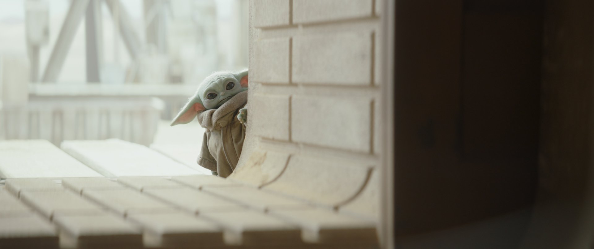 Grogu (Star Wars) — Baby Yoda peeks from behind a wall in The Mandalorian TV show; 2K Quad HD PC desktop wallpaper/background.