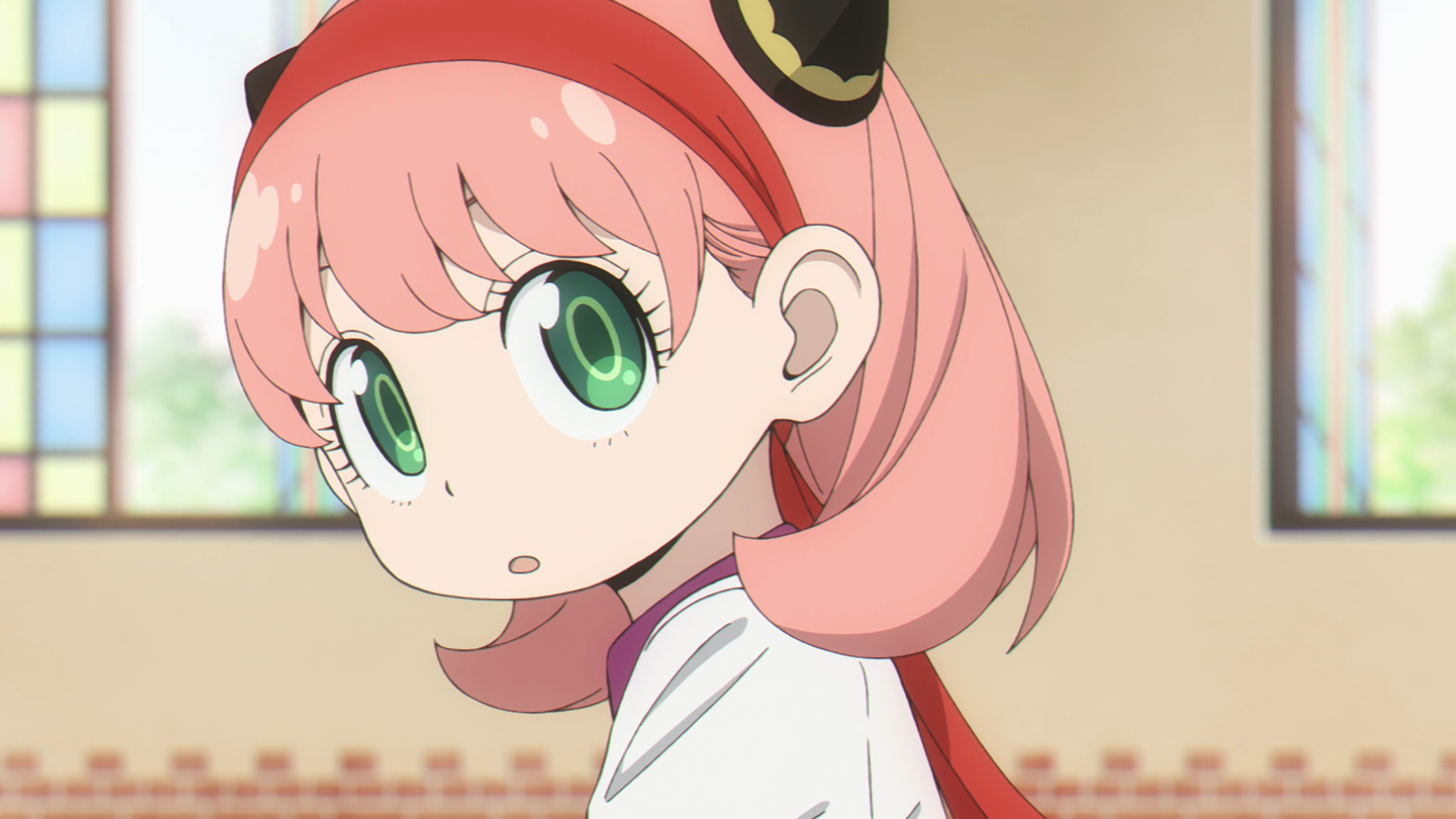 HD PC desktop wallpaper of Anya Forger (Spy x Family): close-up anime portrait with pink hair, big green eyes, red headband, looking over her shoulder in a softly lit interior.