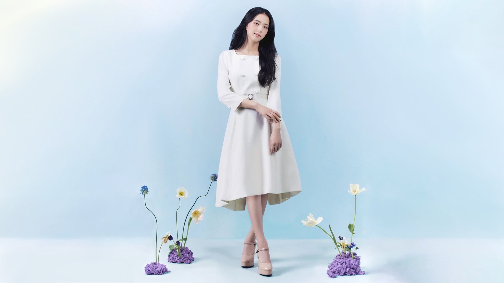 HD PC wallpaper featuring Jisoo of BlackPink standing gracefully in a white dress against a soft blue background with delicate flowers.