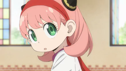 HD PC desktop wallpaper of Anya Forger (Spy x Family): close-up anime portrait with pink hair, big green eyes, red headband, looking over her shoulder in a softly lit interior.