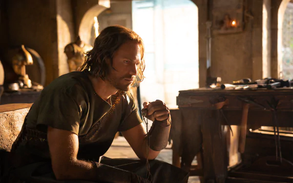 HD PC desktop wallpaper from the TV series The Lord of the Rings: The Rings of Power — a brooding warrior sits in a sunlit forge, bathed in warm golden light.