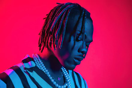 High-definition desktop wallpaper of a man with braided hair, wearing striped attire, against a vibrant red and blue background, tagged with CKay.