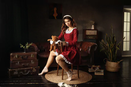 HD PC desktop wallpaper featuring a woman model in a vintage red dress sitting on a chair, holding a teddy bear, in a warmly lit, rustic room setting.