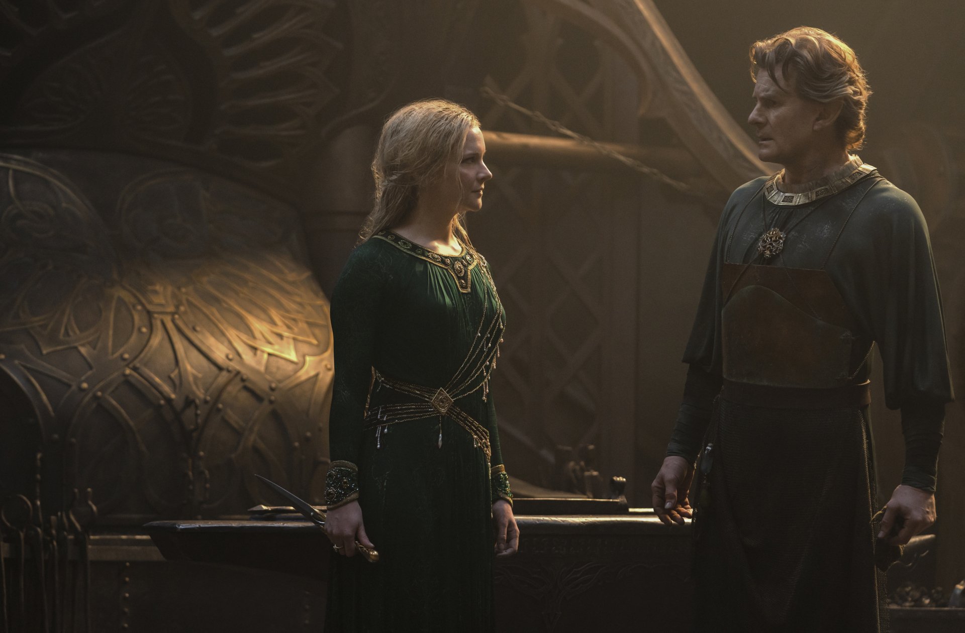 HD desktop wallpaper featuring Morfydd Clark as Galadriel in the TV show The Lord of the Rings: The Rings of Power, standing in a dimly lit, ornate setting.