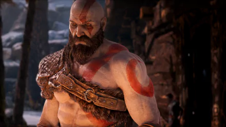 HD PC desktop wallpaper/background of Kratos (God of War, 2018) — video game hero with red warpaint and beard, leather armor strap, and stern gaze in a snowy, ruined canyon.