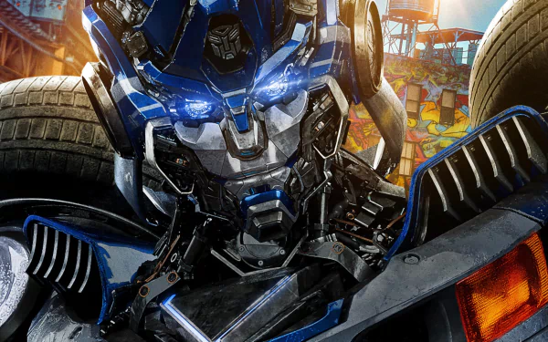 HD PC desktop wallpaper featuring a close-up of a blue Transformer robot from the movie Transformers: Rise of the Beasts with vibrant urban background details.